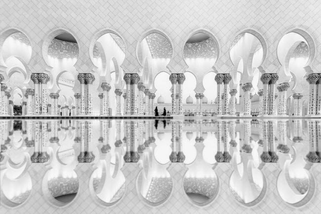 Hai người phụ nữ in bóng xuống mặt nước dưới hồ trước nhà thờ ở Sheikh Zayed, Các tiểu vương quốc Ả Rập thống nhất.